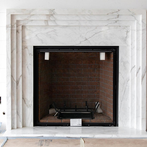 Carrara marble surround installed over traditional brick fireplace