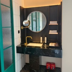 Boutique hotel bathroom with round LED mirror and textured glass door