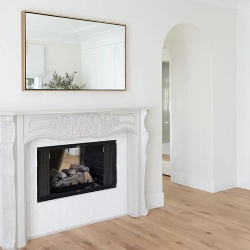 Clean statement marble fireplace mantel with metal framed mirror